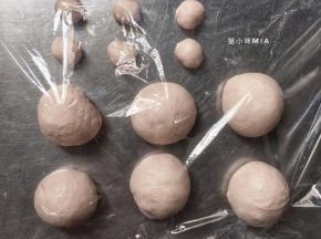 将发酵好的面团先分出一份30克的面团，将用来做小猫咪的耳朵，剩余的面团平均分成15份，都揉圆用保鲜膜盖好醒发10分钟，醒发完后，15份揉圆的面团放烤盘，30克的面团平均分成30份做成耳朵的样子
（我这里只做了6个迷你汉堡，其它的就做成正常尺寸的小餐包了）