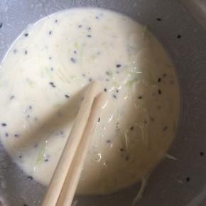 加入适量水，搅拌成浓稠的面糊。再撒一勺黑芝麻搅拌均匀。