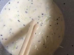 加入适量水，搅拌成浓稠的面糊。再撒一勺黑芝麻搅拌均匀。