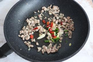 肉末变色后，放入葱、姜、蒜、干辣椒、花椒进行翻炒。