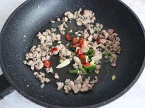 肉末变色后，放入葱、姜、蒜、干辣椒、花椒进行翻炒。