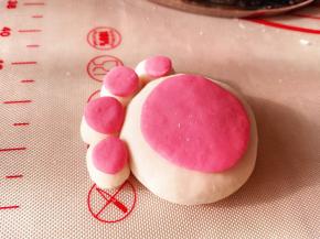 7.	再取另一种颜色的面团，一块大的，4个小的，分别按压成圆饼状，粘在之前的猫爪上，一个猫爪汤圆就做好了，