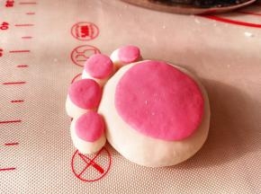 7.	再取另一种颜色的面团，一块大的，4个小的，分别按压成圆饼状，粘在之前的猫爪上，一个猫爪汤圆就做好了，