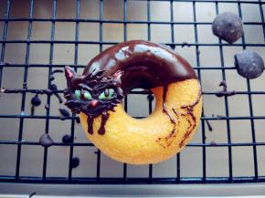 将小猫的头部画好后，放入冰箱冷藏片刻，凝固后取下，挪到甜甜圈上，并画出前后四肢。