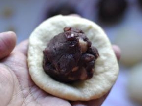 7、然后把面团压扁，用月饼皮包住豆沙；