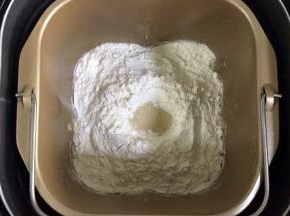 除黄油以外的面包材料都放入面包桶内（先液体后粉类的顺序，糖和盐对角放），在面粉中间挖个洞，把酵母粉倒入，启动和面程序。
