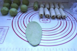 10、在把包好的酥皮2面团也擀开，成牛舌形状，由上往下卷起来，收口朝下，放在面垫上