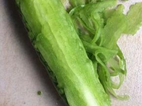 苦瓜洗净后，用刨丝器慢慢刮擦表皮，知道看见白瓤后停下