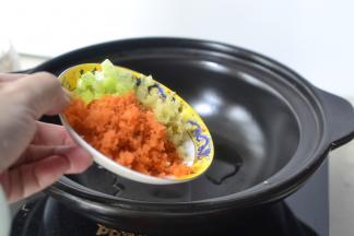砂锅烧热加入适量的油然后将葱姜和胡萝卜蓉放入翻炒均匀