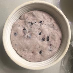 轻拍面团排气整型放入预先洒好面粉的藤篮中。