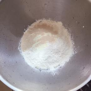 将除黄油外的其它材料倒入溶器里，牛奶和蛋液首先放入，再将白糖和盐各放一个角落，再放面粉，奶粉，最后倒入酵母