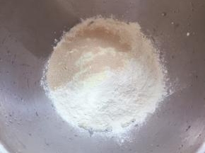 将除黄油外的其它材料倒入溶器里，牛奶和蛋液首先放入，再将白糖和盐各放一个角落，再放面粉，奶粉，最后倒入酵母