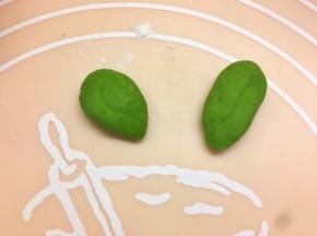 取两个菠菜面团，揉圆压成叶子形状