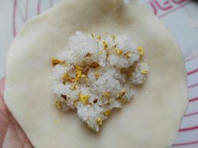 用手延展开来，四周的皮可以薄些（四周做成底的，底不要太厚哈～）中间放入砂糖跟桂花