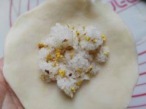用手延展开来，四周的皮可以薄些（四周做成底的，底不要太厚哈～）中间放入砂糖跟桂花