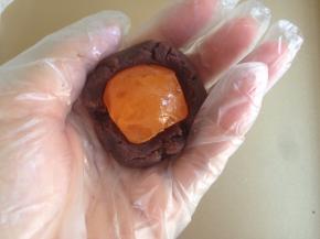 称量好馅料，咸蛋黄和豆沙馅加起来一共是40克。将豆沙馅搓圆后，用拇指在中间压个坑，放入蛋黄