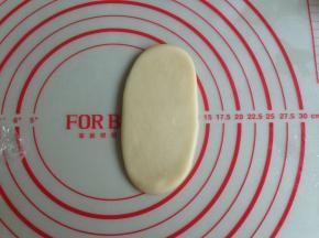 将松驰后的油酥皮压扁，用擀面棍擀成牛舌状