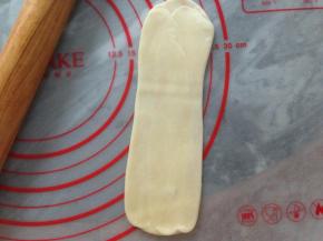 松驰后的油酥皮压扁，用擀面棍擀长