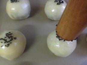 东菱K40C烤箱预热180度，蛋黄打散，用毛刷粘蛋黄液涂蛋黄酥表面，2分钟后再涂一次。擀面棍粘湿，粘上黑芝麻，然后再粘在蛋黄酥上面