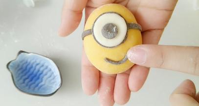 如图，粘上黑细条在白面片周围。在粘上黑色眼睛，及嘴巴。