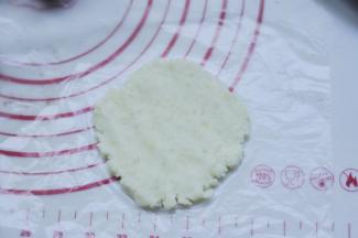 8、取一个白薯泥球，放在保鲜膜上，隔着袋子压成片状。