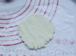 8、取一个白薯泥球，放在保鲜膜上，隔着袋子压成片状。