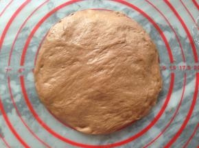 将静置后的面团，光滑的上面朝下，用手压成圆形，大小就按揉面垫上5寸大小即可