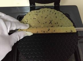 一定要马上卷起，不然很快会脆的，将蛋卷棒放在煎好的蛋卷上，带上手套快速卷起就ok