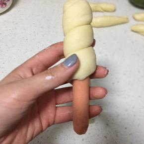 然后取一根火腿肠，用面长条卷起来，把两头都塞进面里