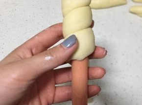 然后取一根火腿肠，用面长条卷起来，把两头都塞进面里