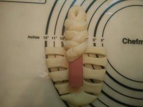 将两边的面条依次交叉叠加在香肠上面，如图。