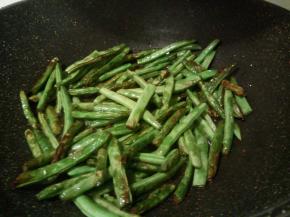 锅中稍微放多些油，用大火炸四季豆，大概3，4分钟这样，炸至外皮微皱即捞出盛起