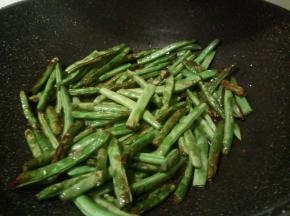 锅中稍微放多些油，用大火炸四季豆，大概3，4分钟这样，炸至外皮微皱即捞出盛起