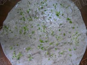 发好的面团揉匀，擀成大的薄面皮；抹上油酥，撒上葱粒。