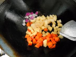 锅中余油，爆香洋葱，下土豆、胡萝卜，加少许盐翻炒均匀。