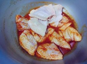 将盐、料酒、奥尔良腌料和水调匀后，倒入鸡翅中拌匀