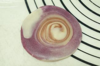 切面朝上，用手压扁，再用擀面杖擀成中间稍厚，边缘薄的圆形，中心尽量归中。