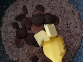 将搅拌好的面糊倒入不粘锅中，一定要不粘锅。加入黄油和巧克力币，加小火翻炒。