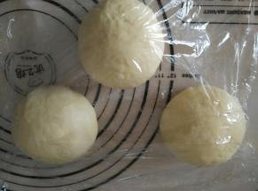 取出轻柔排气，平均分成三份。揉圆盖保鲜膜醒10分钟