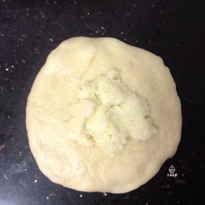 把面团擀成圆形，包入适量的椰蓉馅，收紧口。