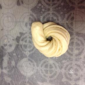 打开折叠的面皮胚，左右手各捏住一端面团，像拧衣服一样，一手向下，一手向上扭曲，围成一个圆形，收口向下