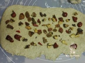 擀开后翻面在擀成长方形，一边压薄，均匀的撒上核桃干和混合果干。从上至下卷起，收紧口。
