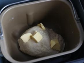 20分钟后加入软化的黄油，继续揉面。