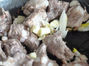 锅里倒入油，放入排骨翻炒，同时加入葱、姜、蒜。