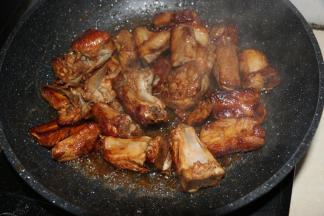 放入排骨块迅速翻炒，使得每一块排骨都裹上糖色。