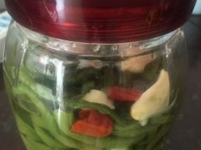 豇豆洗干净，切段开水煮一下，只要变色即可，不要煮熟，捞出沥水，用盐码下，放入密封瓶中，加烧酒（根据豇豆多少下，不要多）放入切好的辣子和拍碎的大蒜头，盖上密封盖，放置三天