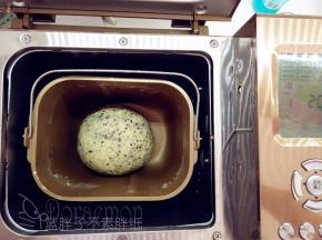 取出静置好的面团，加入黄油和酵母，启动2个揉面程序（20分钟），在最后3分钟的时候加入黑芝麻，揉到完全阶段。