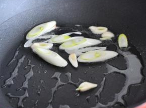 锅里倒入油，放入葱段和蒜爆香。