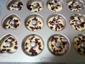 裱花袋剪小口，先在模具里挤入三分之一的面糊，然后撒上一层蔓越莓