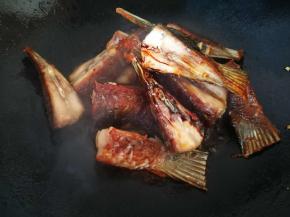 锅里再次放入一点油，加入生姜大蒜煎出香味，放入煎好的鱼尾翻炒下，注意不要把鱼尾戳散了